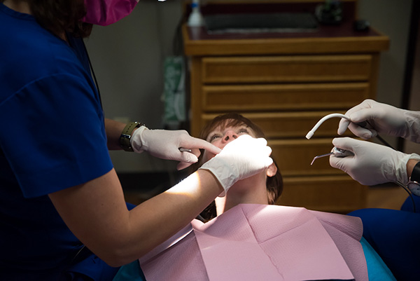 Dentist examining a patient's mouth with dental tools.